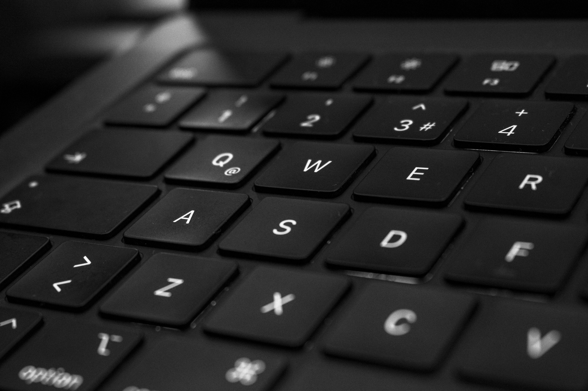 Primer plano en blanco y negro de un teclado negro, con el foco en las teclas centrales.