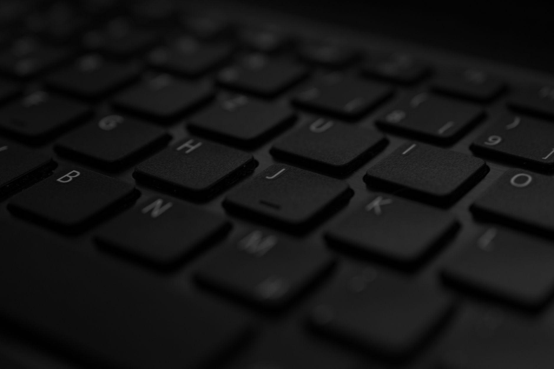 Primer plano de un teclado de portátil negro con iluminación suave y enfoque selectivo, ambiente de trabajo desde casa.